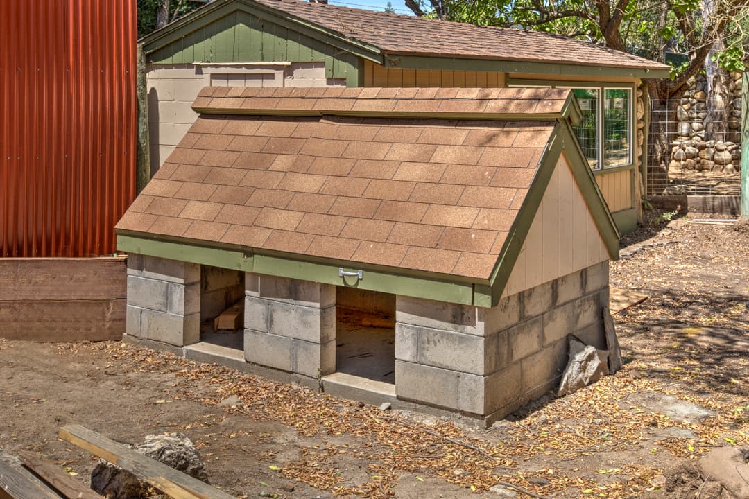 Outdoor dog house built with concrete blocks and a shingled roof